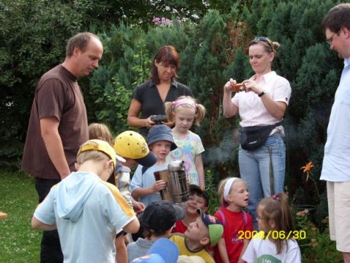 Grupp von Kindern und Erwachsenen im Garten, die miteinander spielen und lachen.