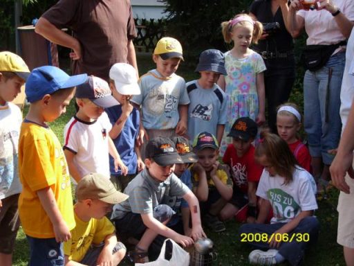 Eine Gruppe von Kindern in bunten Hüten versammelt sich im Freien.